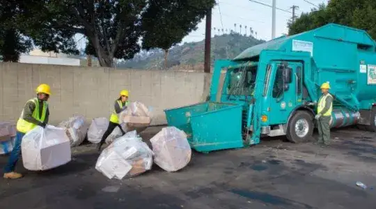 Sanitation truck and workers picking up bulky items